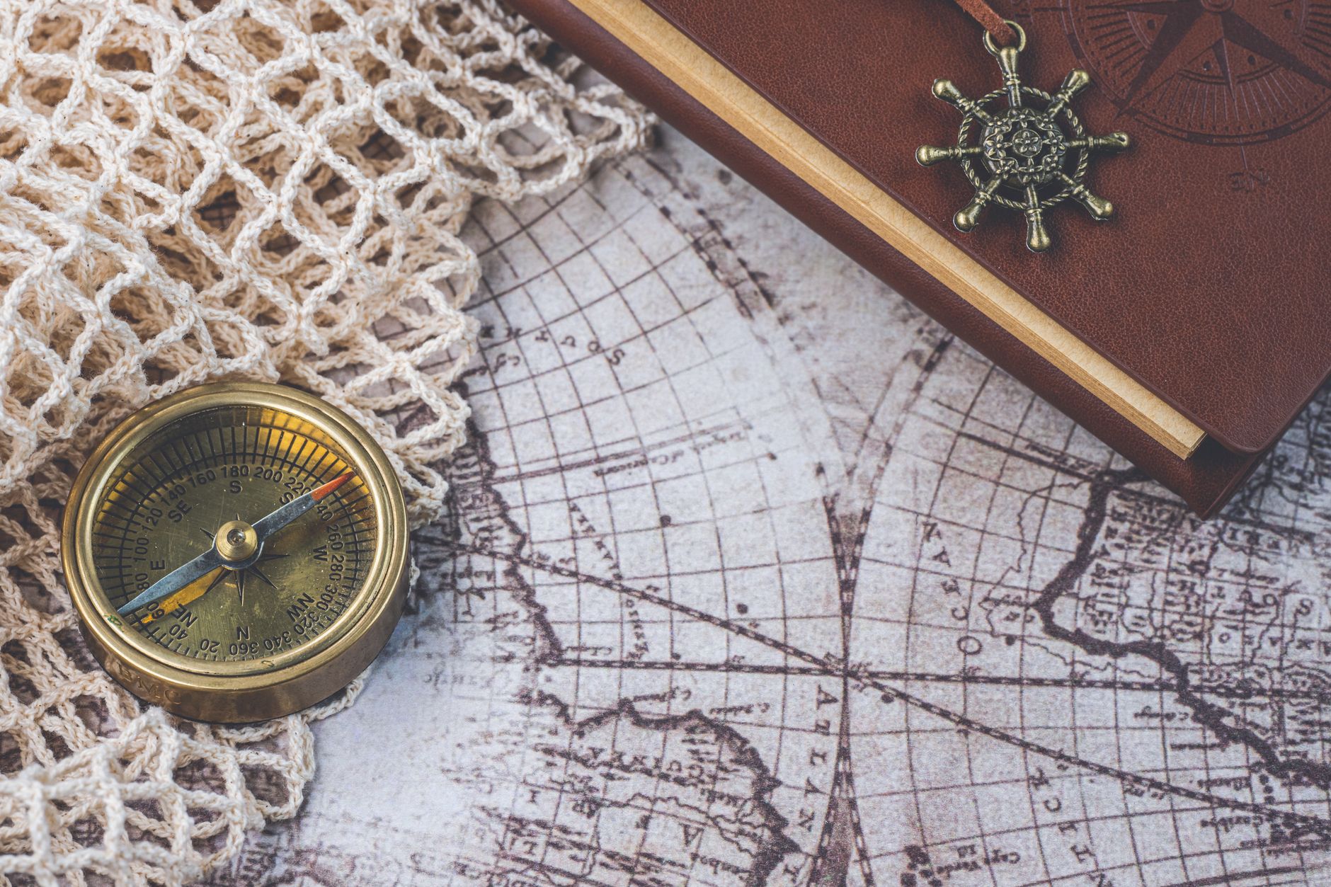 Map, compass, and travel notebook laid out carefully on rustic table